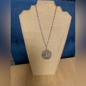 Silver necklace with a filigree pendant and a chain.